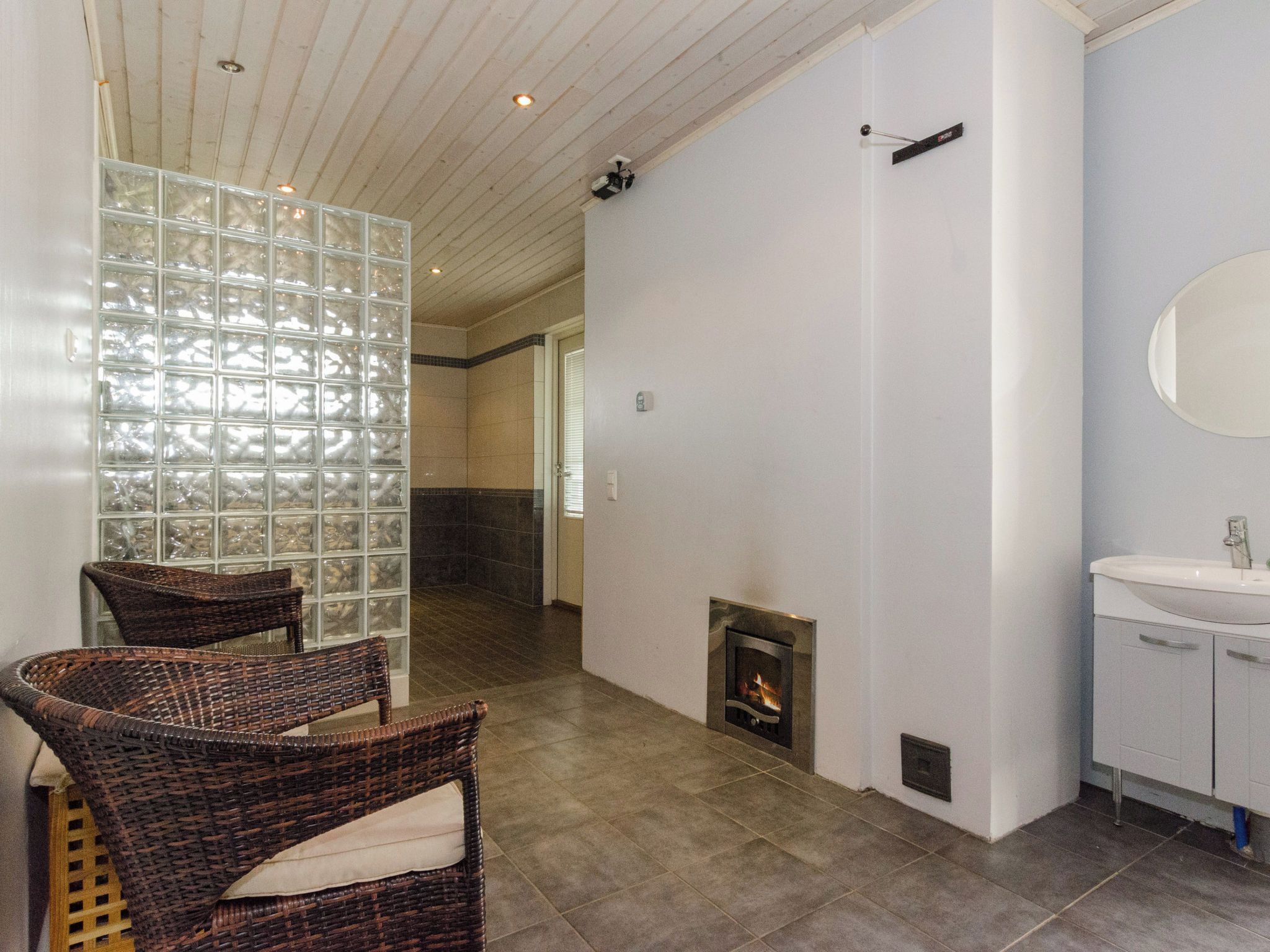 Un baño moderno con chimenea, un espejo grande y sillones de mimbre.