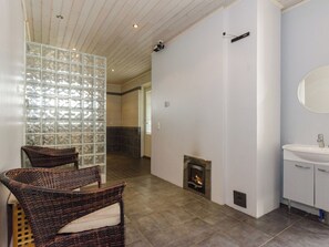 Une salle de bain moderne avec une cheminée, un grand miroir et des fauteuils en osier.