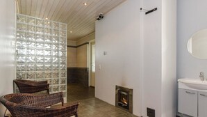 A modern bathroom with a fireplace, wicker chairs, and a large mirror. - Vacation home Kaisla by Interhome (Joensuu)