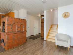 Een kamer met een open haard van baksteen, een houten trap en een stoel.