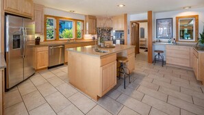 A spacious kitchen with wooden cabinets, a large island, and a built-in oven. - Waterfront Retreat w/ Sauna | Whales & Sunrises (Friday Harbor)