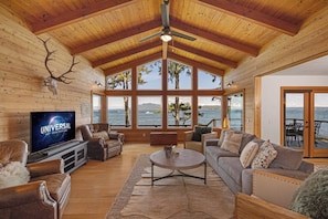 A spacious living room with a large television, wooden ceiling, and a view of the ocean. - Waterfront Retreat w/ Sauna | Whales & Sunrises (Friday Harbor)