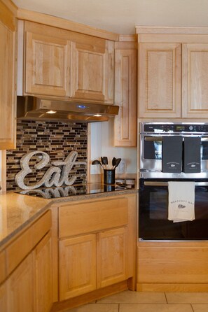 A kitchen with wooden cabinets, a stainless steel range hood, a brick backsplash, and a stainless steel oven. - Waterfront Retreat w/ Sauna | Whales & Sunrises (Friday Harbor)
