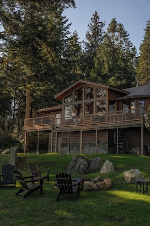 A two-story log cabin with a deck and outdoor seating area.