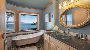 A bathroom with a freestanding bathtub, a large mirror, and a view of the sea. - Waterfront Retreat w/ Sauna | Whales & Sunrises (Friday Harbor)