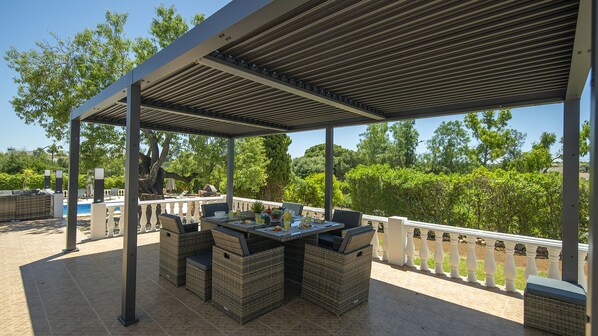 An outdoor patio with wicker furniture, a pool, and a view of trees. - Villa Haven (Lagoa)