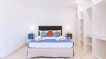Un dormitorio ordenado con una cama, dos mesitas de noche y una estantería empotrada.