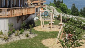 Un hôtel à plusieurs étages doté de balcons en bois, d’une piste de ski et surplombant un paysage montagneux.