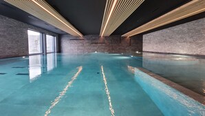 Une piscine intérieure spacieuse au design moderne, caractérisée par une forme longue et étroite et une surface lisse et réfléchissante.