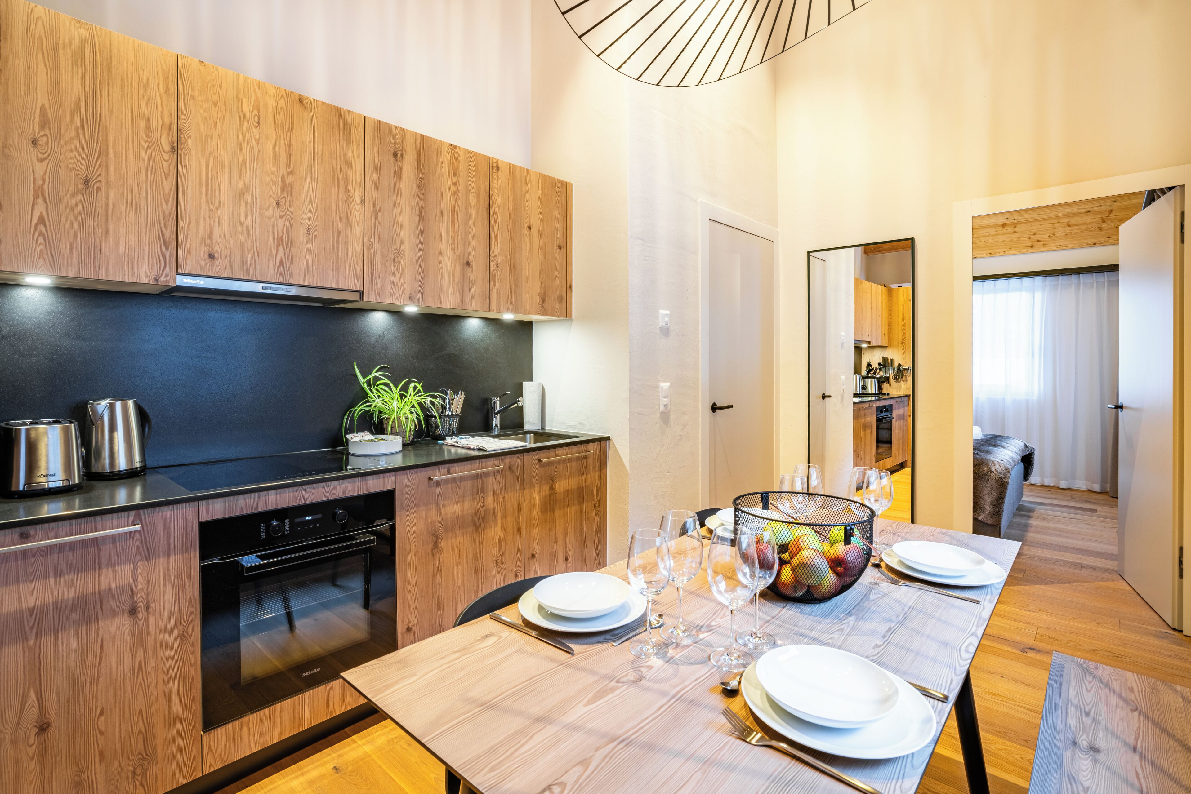 Una cucina moderna con mobili in legno, forno integrato e zona pranzo con tavolo apparecchiato per quattro.