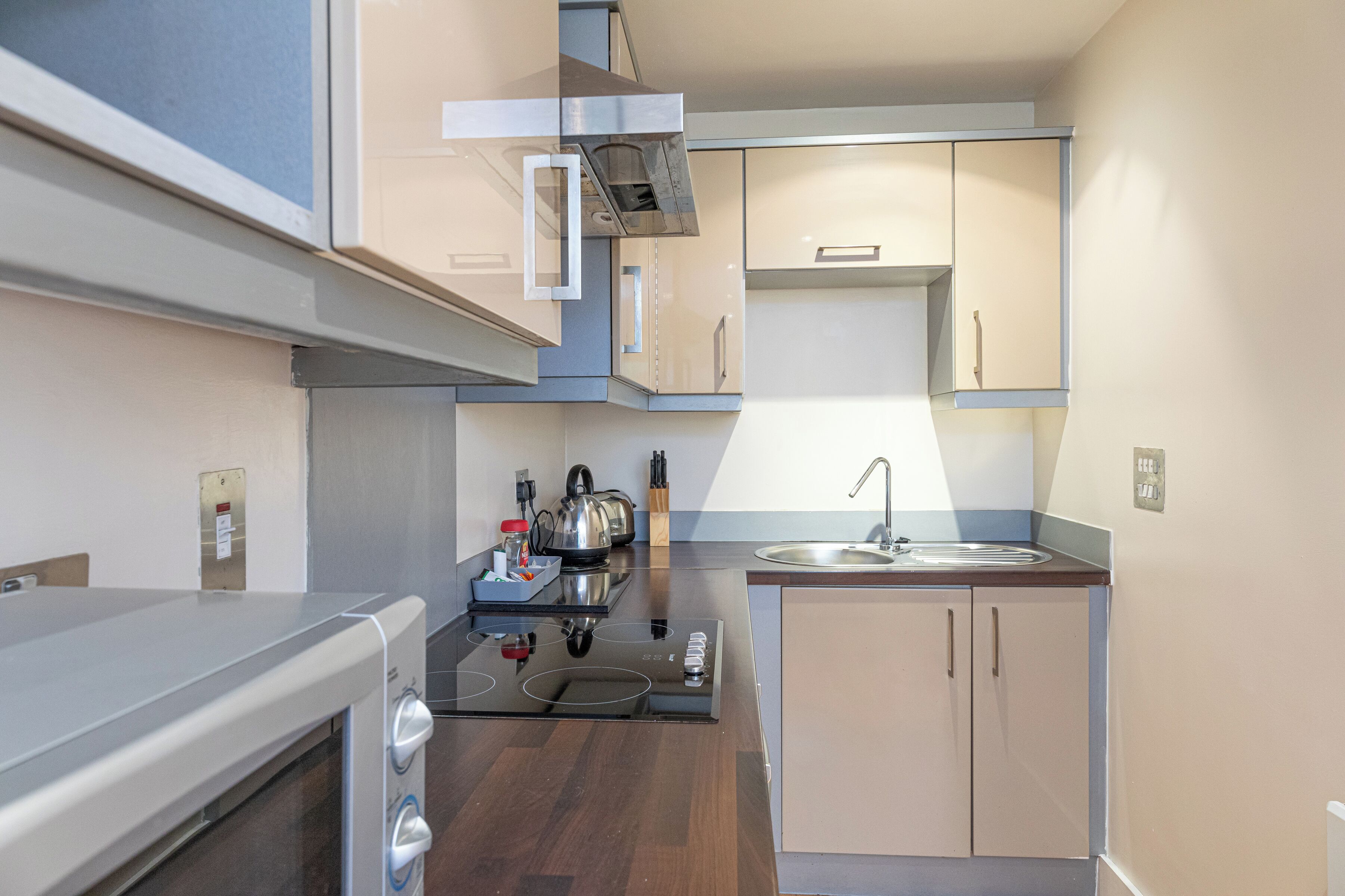 Una cucina compatta con forno integrato, piano cottura, lavello e pensili in legno.