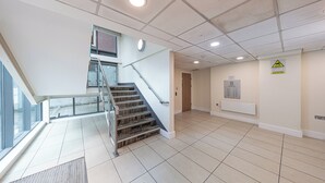 A spacious lobby with a staircase, a clock, and a fire safety sign. -  Quayside Newcastle (Newcastle upon Tyne)