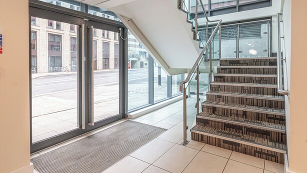 A modern building entrance with a glass door, a staircase, and a view of the street outside. -  Quayside Newcastle (Newcastle upon Tyne)