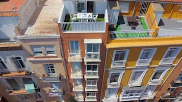 Un edificio residencial de varios pisos con balcones, terraza en la azotea y un tendedero visible.