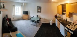 A compact living space with a dining area, kitchenette, and a television. - Landau House (Bristol)