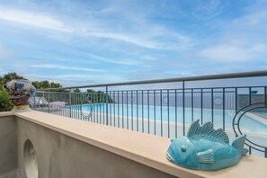 Blick auf einen Pool unter blauem Himmel, mit einer dekorativen Fischskulptur.