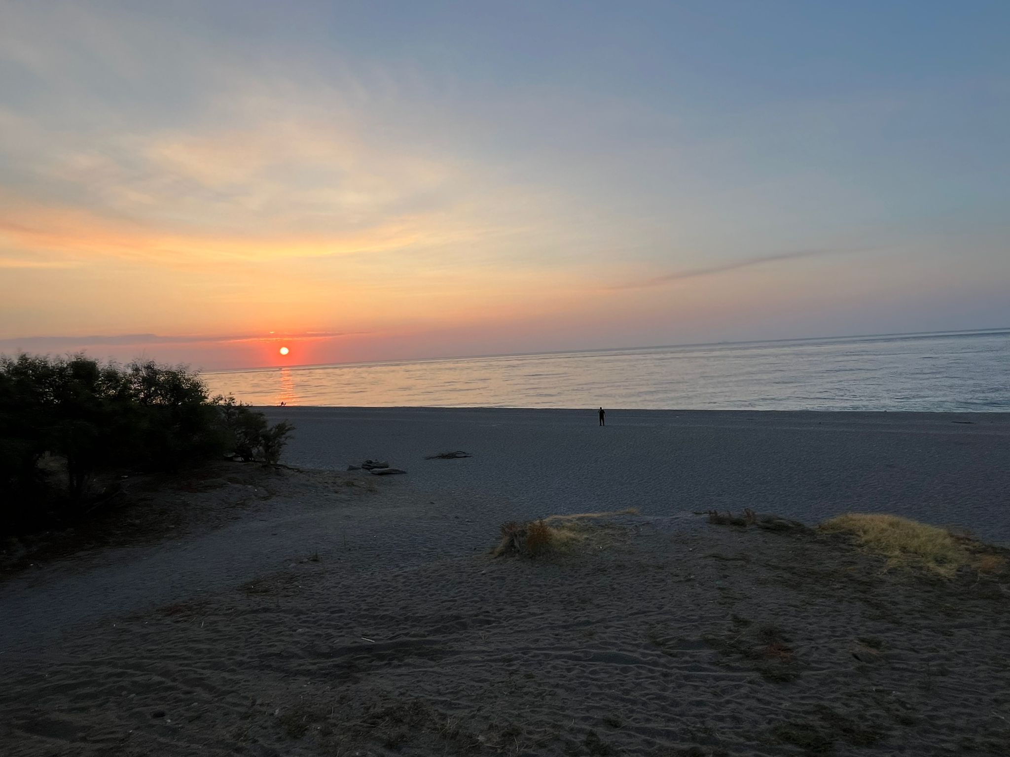En strand vid solnedgången med en klar himmel och ett lugnt hav.