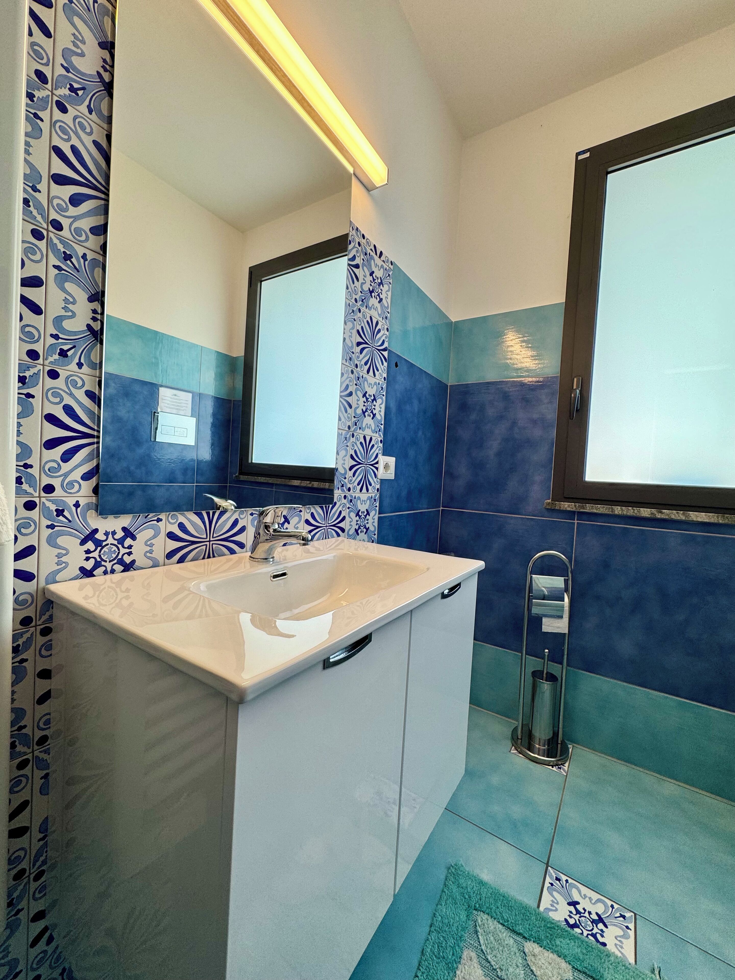 A bathroom with a sink, mirror, and patterned tiles.
