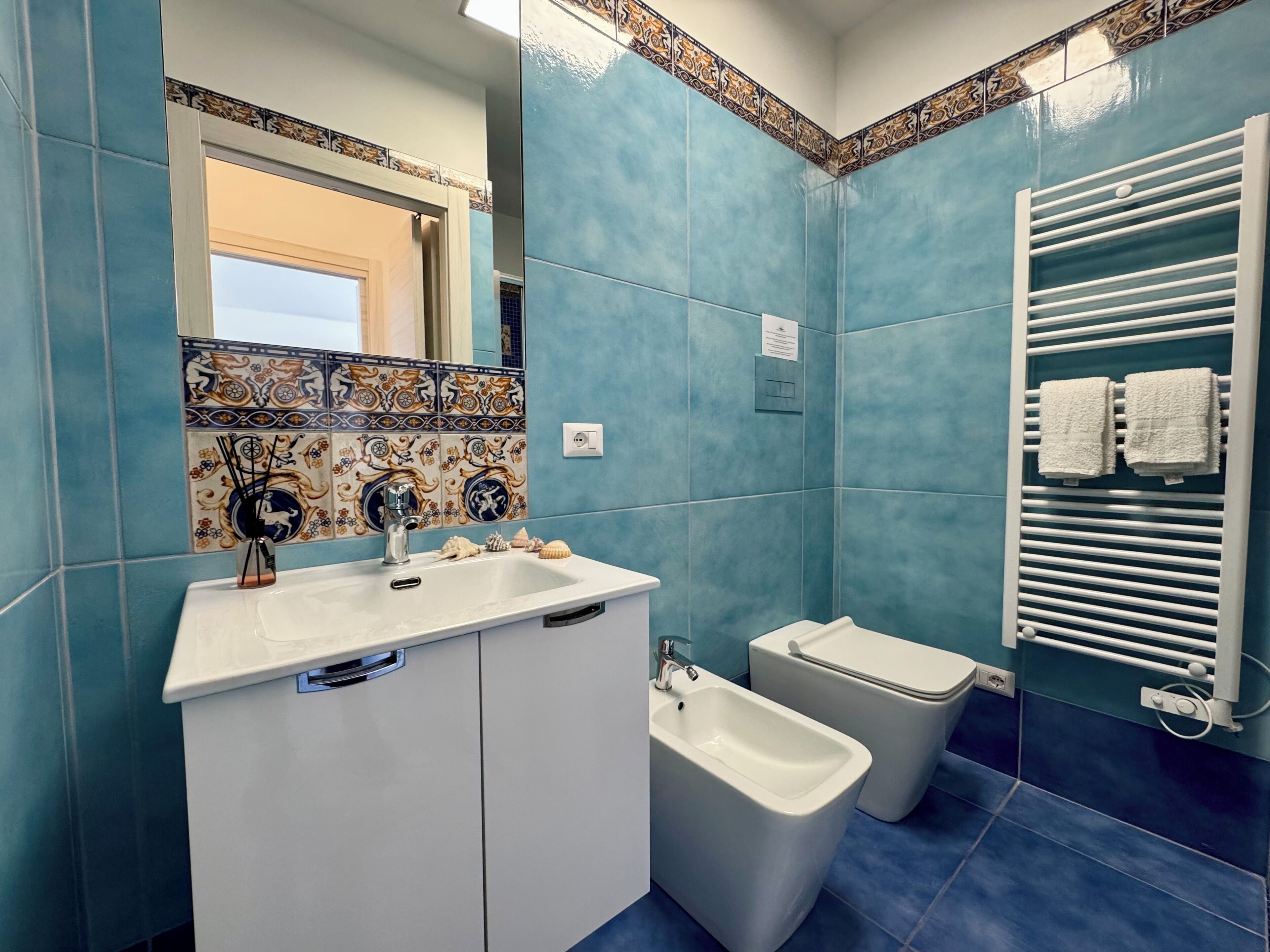 Un baño con lavamanos, bidé y perchero para toallas.