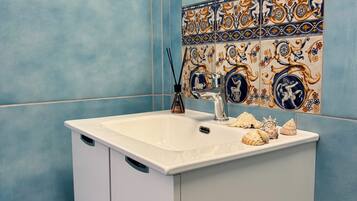 Un baño con un lavamanos blanco, azulejos azules y azulejos decorativos sobre el lavamanos.