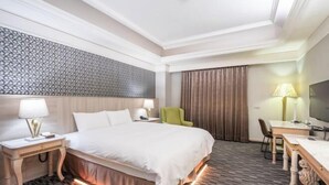 Una habitación de hotel con cama, mesitas de noche, escritorio, silla y televisión.