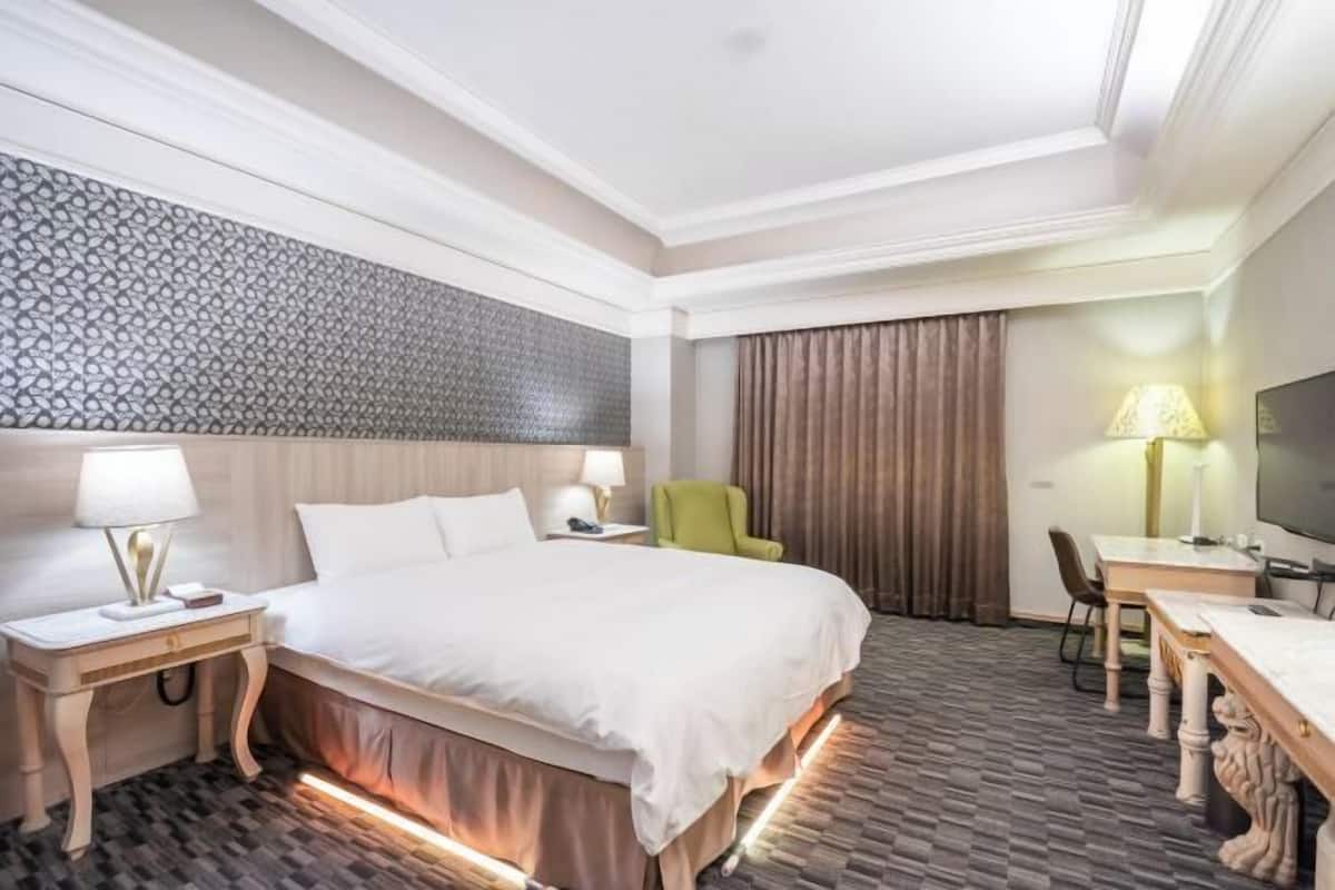 Una habitación de hotel con cama, mesitas de noche, escritorio, silla y televisión.