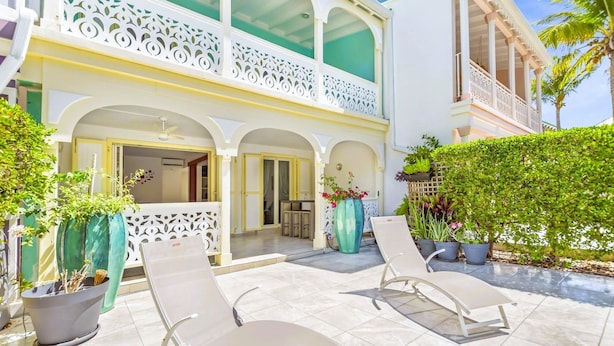 A hotel with a balcony, lounge chairs, and potted plants. - Villa 6p private pool   Orient Bay Beach (Community of Saint Martin)
