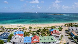 A coastal resort with colorful buildings, a beach, and the ocean. - Villa 6p private pool   Orient Bay Beach (Community of Saint Martin)