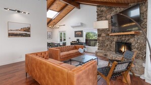 Un salón amplio con chimenea de piedra, sofás de cuero y un comedor con vistas.