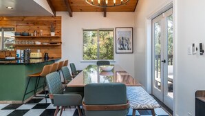 Un comedor con una mesa grande, sillas, una zona de cocina con armarios de madera y vistas por una ventana.