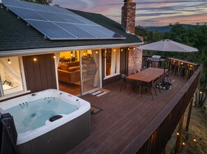Eine Terrasse mit Whirlpool, Sitzgelegenheiten im Freien und Blick auf die Landschaft.
