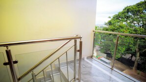 A modern staircase with glass railings and metal handrails, leading to an outdoor area with trees and a view.