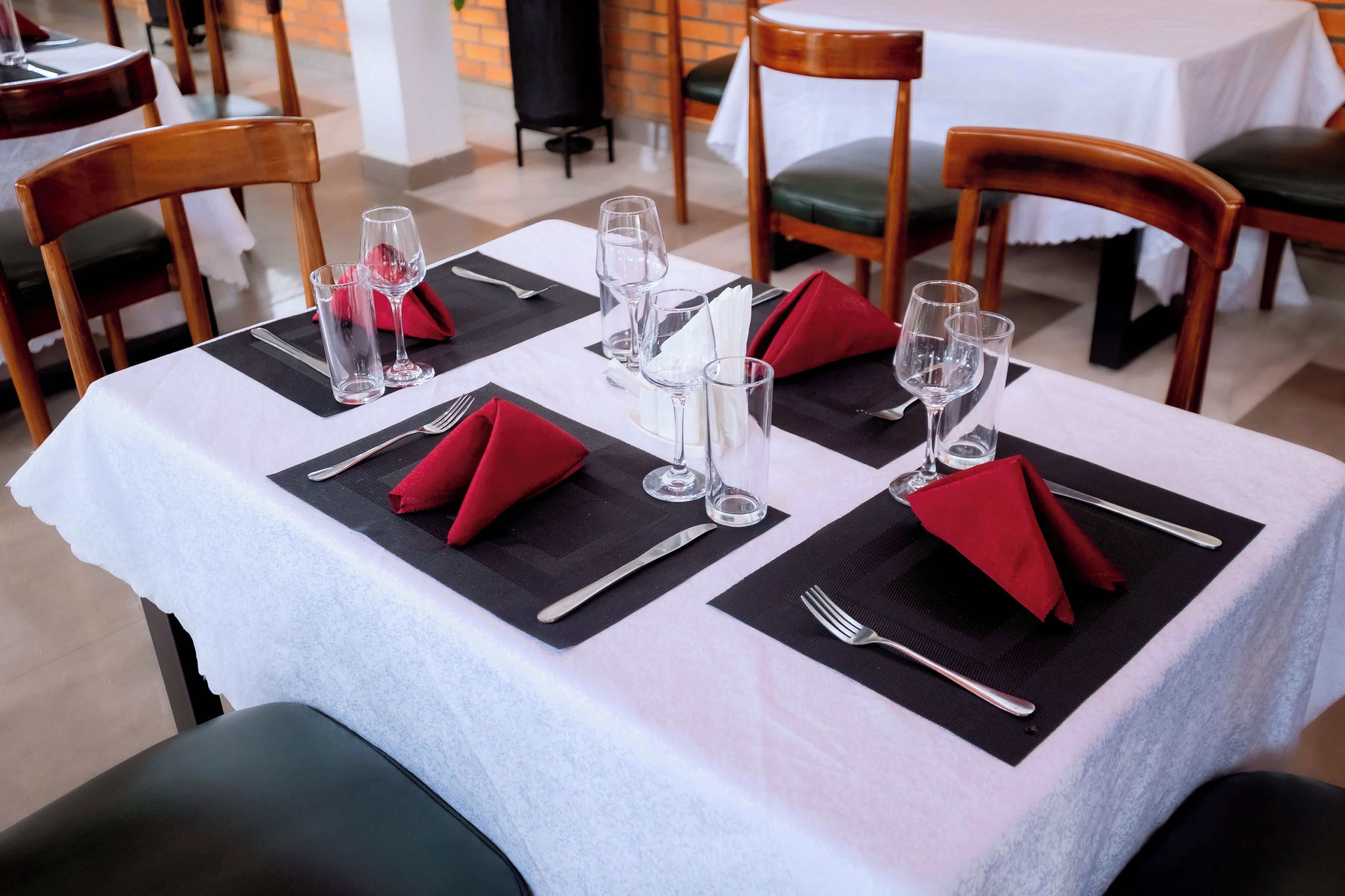 A dining table set with red napkins, clear glasses, and cutlery.
