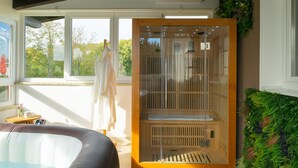 Un cuarto de sauna con un banco de madera, un perchero para toallas y una puerta de cristal.