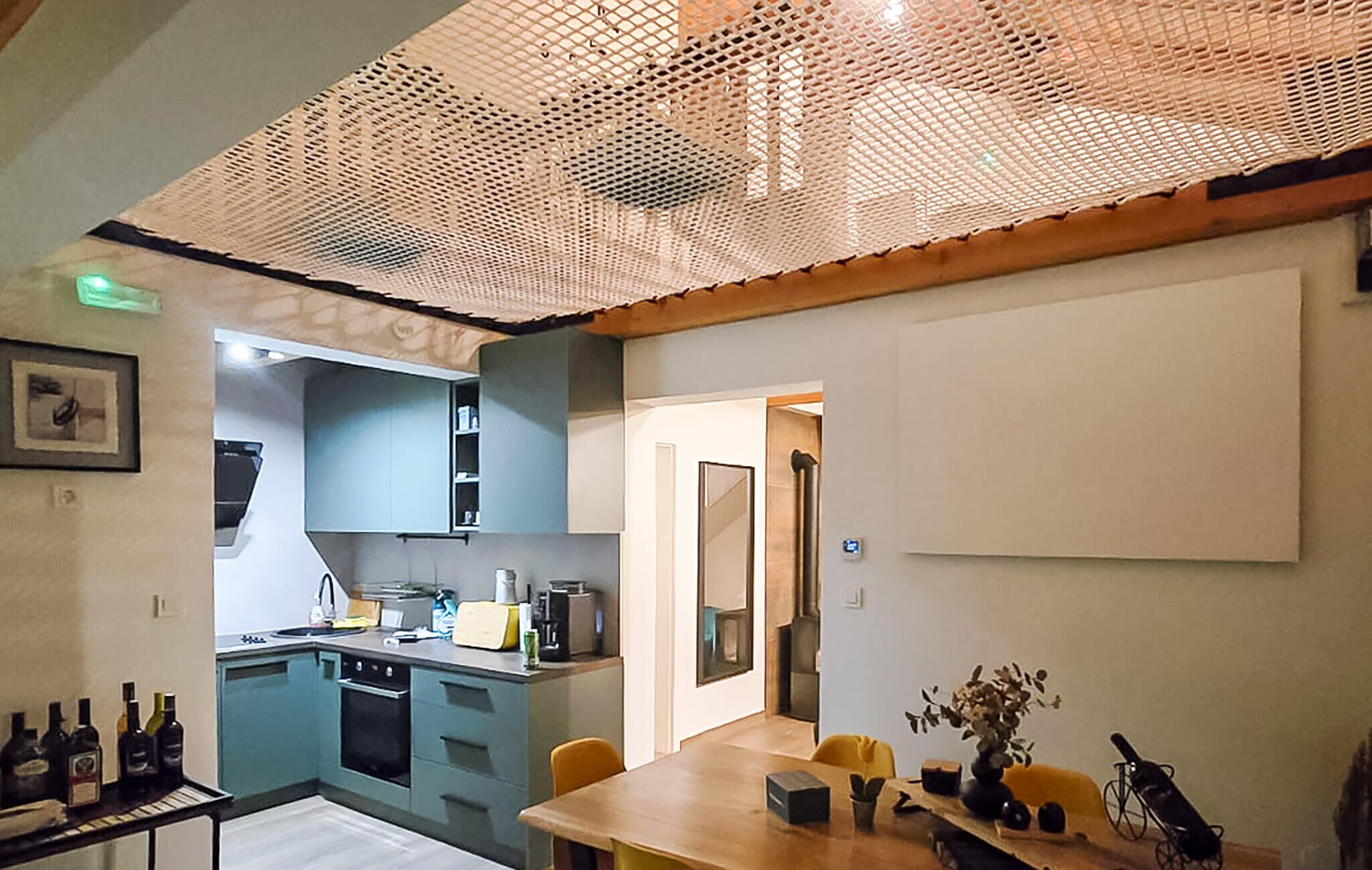 A modern kitchen with blue cabinets, a wooden dining table, and a whiteboard.