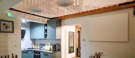A modern kitchen with blue cabinets, a wooden dining table, and a whiteboard.