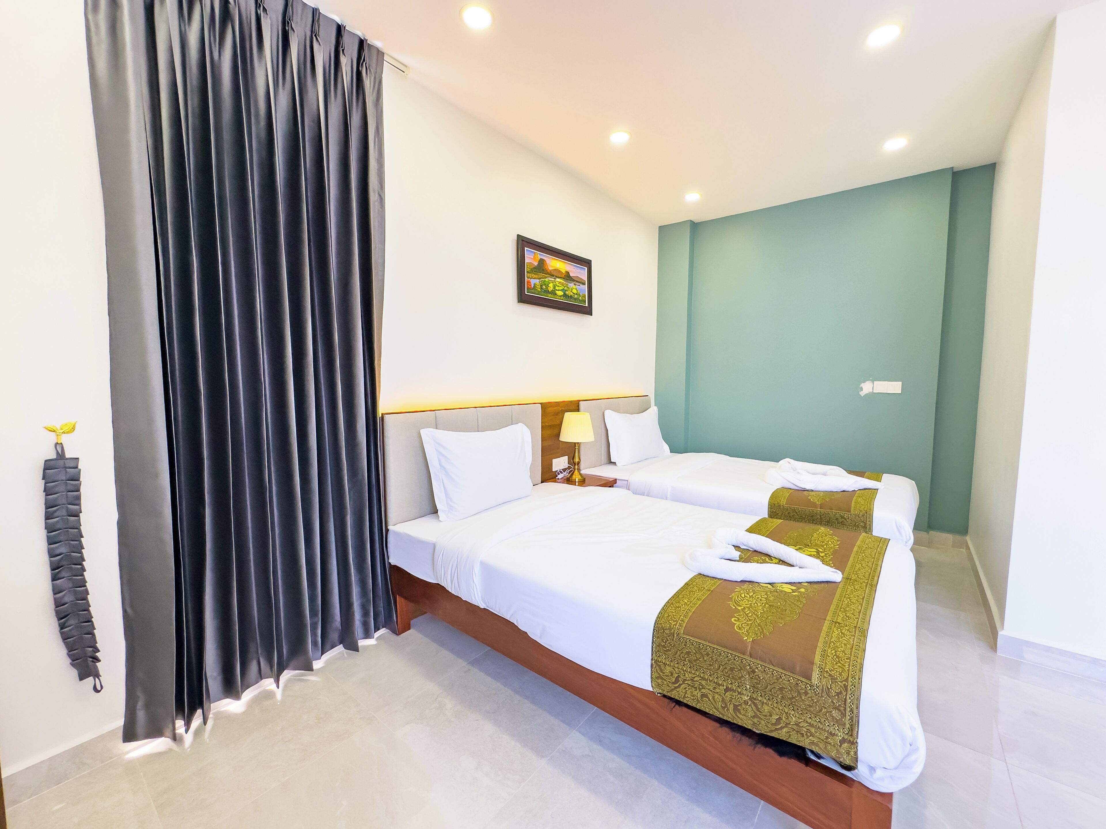 Habitación de hotel con dos camas, un ventanal con cortinas, un cuadro en la pared y una mesita de noche con lámpara.