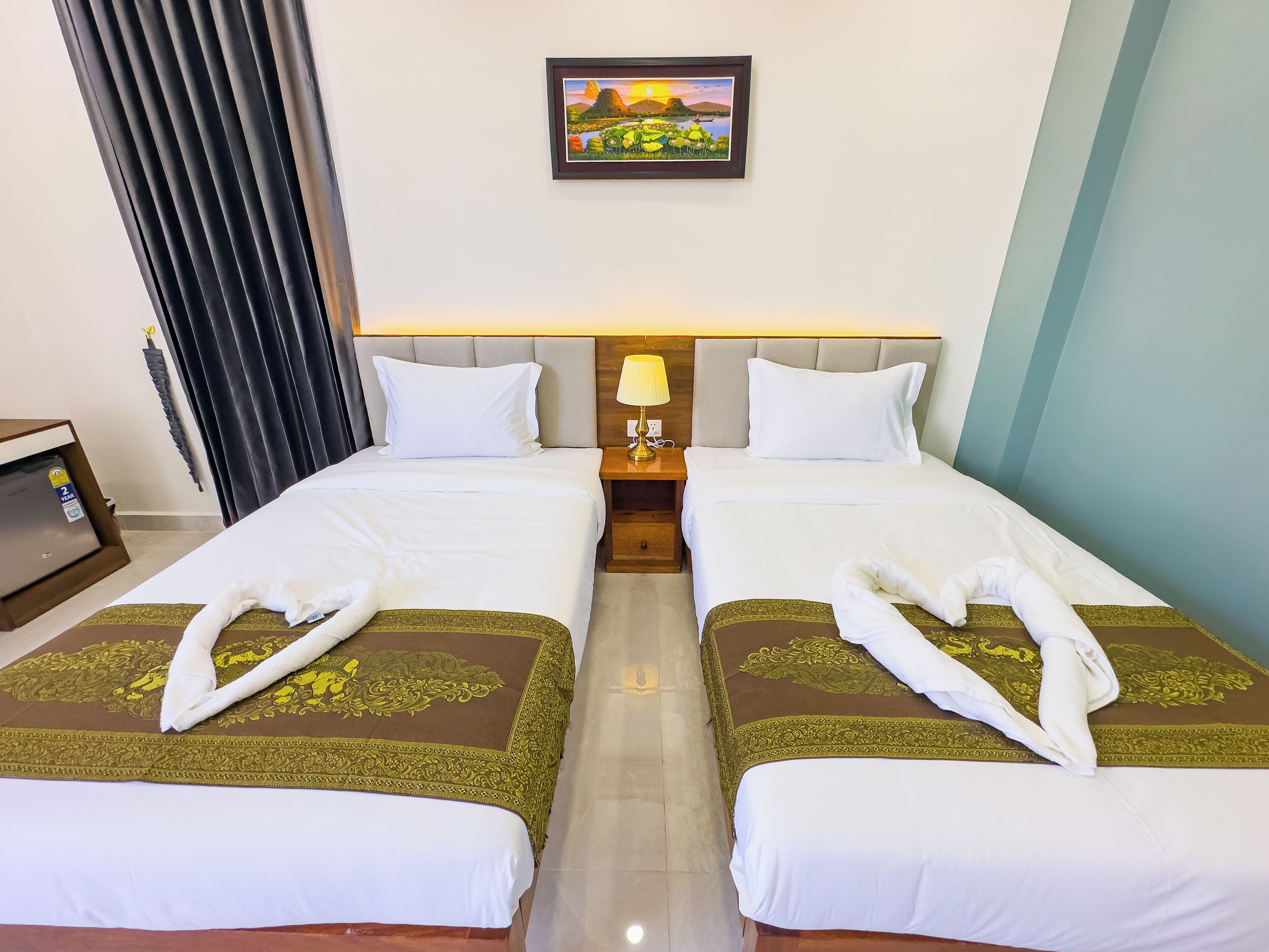 A hotel room with two beds, a nightstand with a lamp, a painting on the wall, and a view of the outdoors.