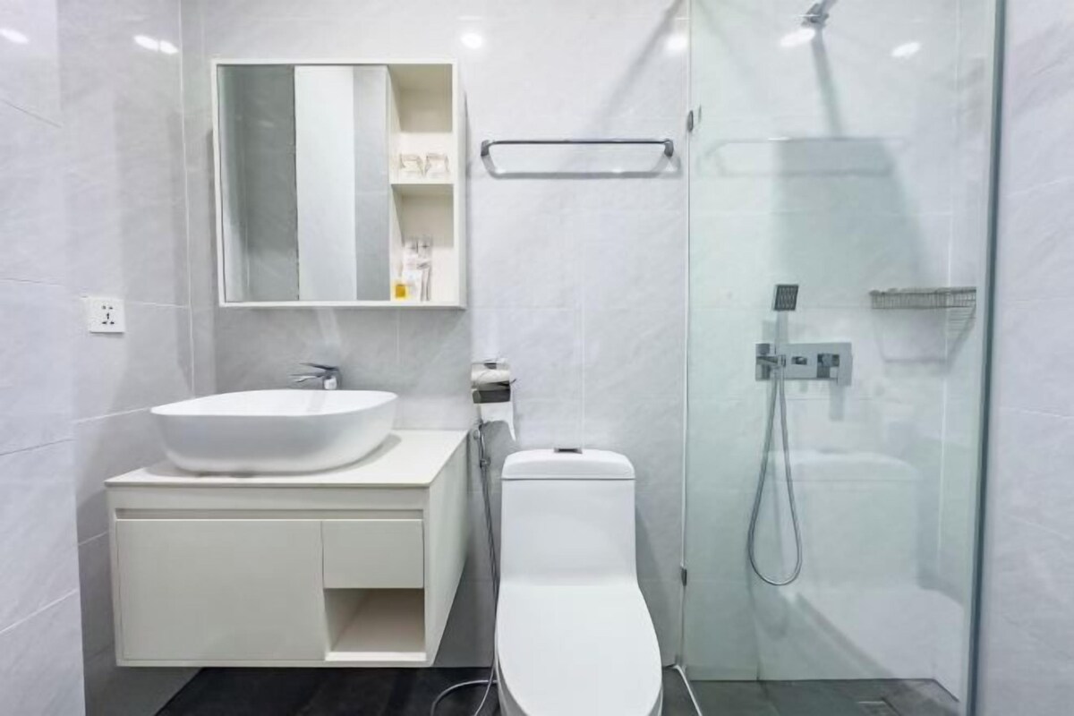 Une salle de bain moderne avec un lavabo blanc, un miroir et des toilettes.