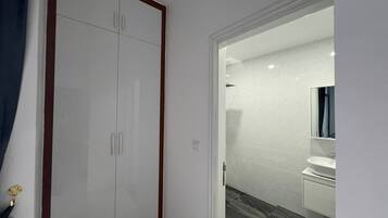 Een hal met een witte kast, een witte wastafel en een spiegel in een badkamer.