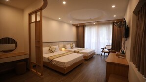 Ein Hotelzimmer mit zwei Betten, einem Schreibtisch, einem Fernseher und einem Fenster mit Vorhängen.