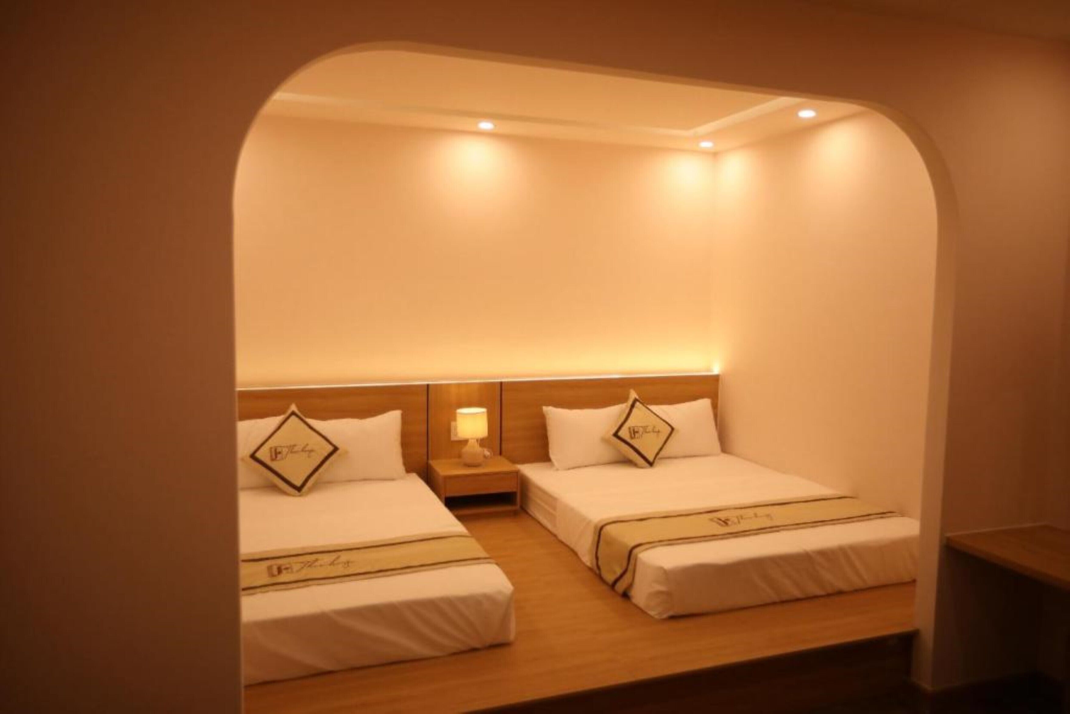 A hotel room with two single beds, each with a headboard, bedside tables, and lamps.