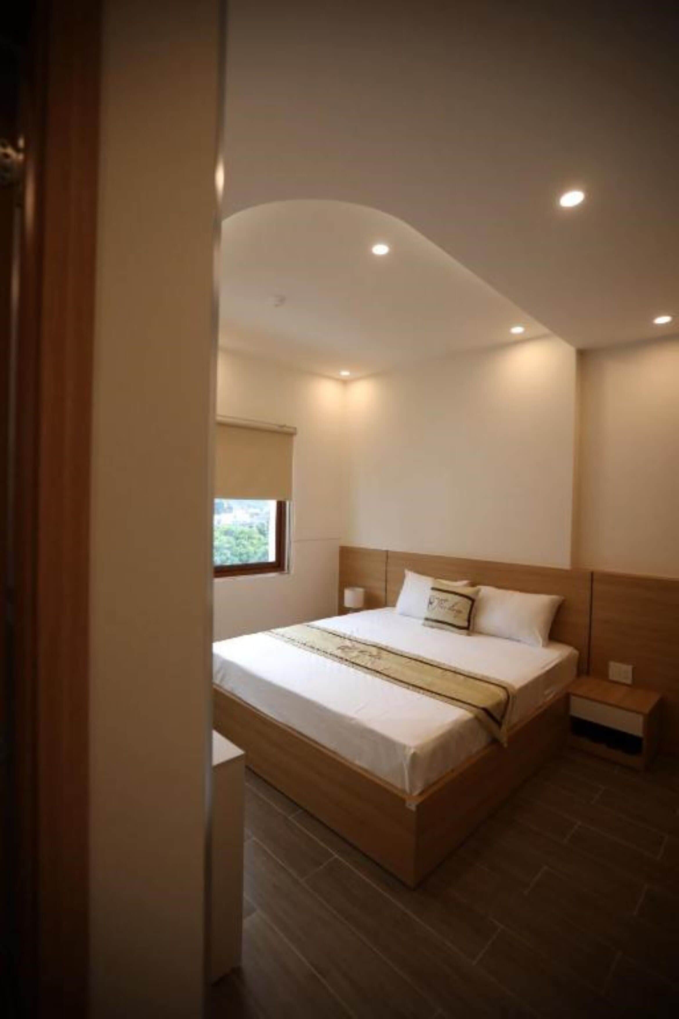 Quarto moderno com cama de madeira, mesa de cabeceira e janela.