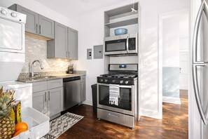 Een koelkast, een kookplaat, kookgerei, borden en bestek