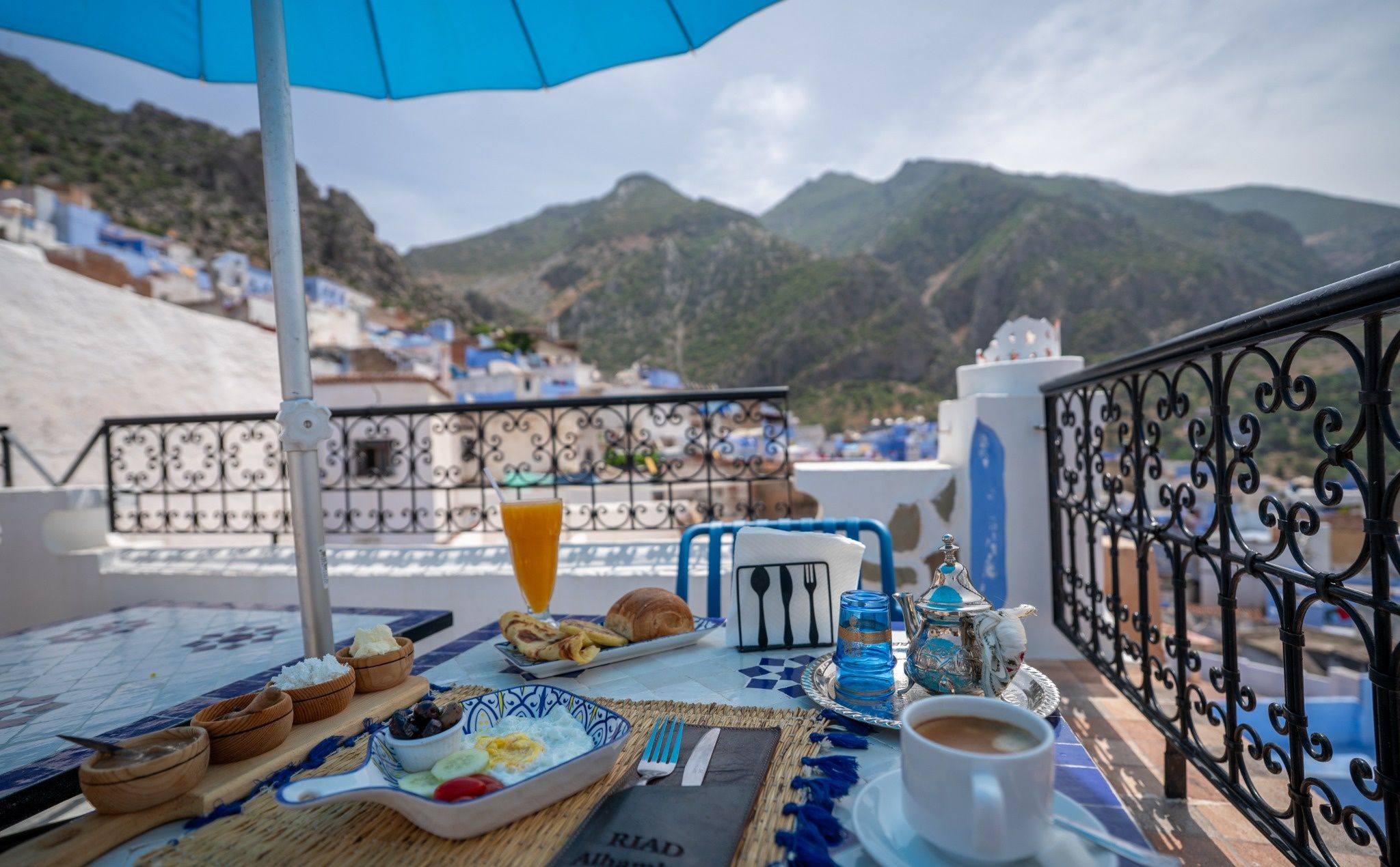 Una mesa servida con alimentos para el desayuno, una taza de café y vistas a un paisaje montañoso.