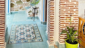 Un pasillo con piso estampado, una planta en maceta y un techo decorativo.