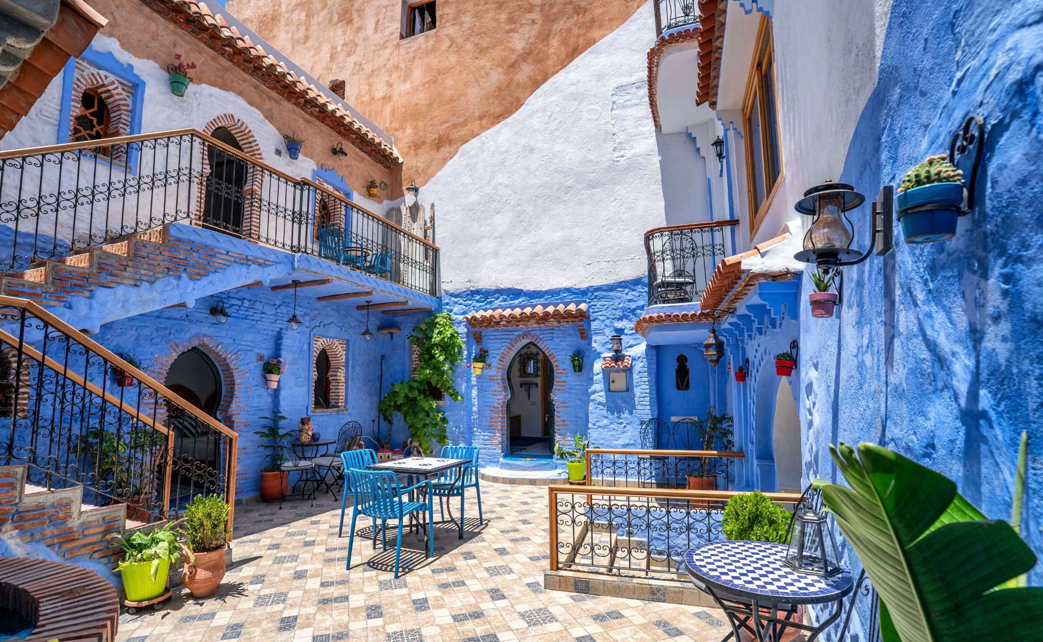 A courtyard with blue-painted walls, a tiled floor, and outdoor seating.