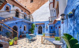 A courtyard with blue-painted walls, a tiled floor, and outdoor seating.