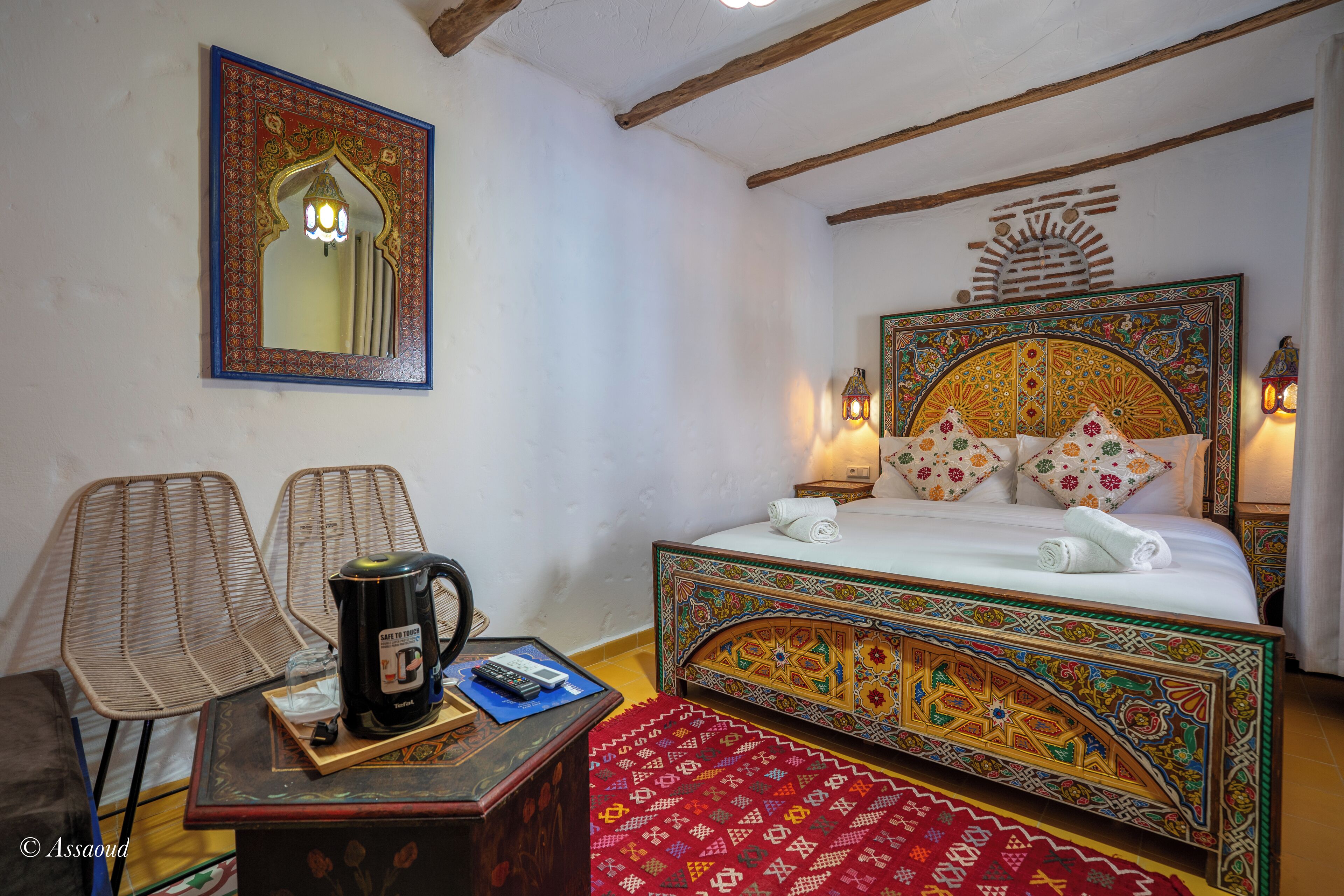 Ein Zimmer mit einem Bett, zwei Sesseln, einem Couchtisch und einer Wandlampe.