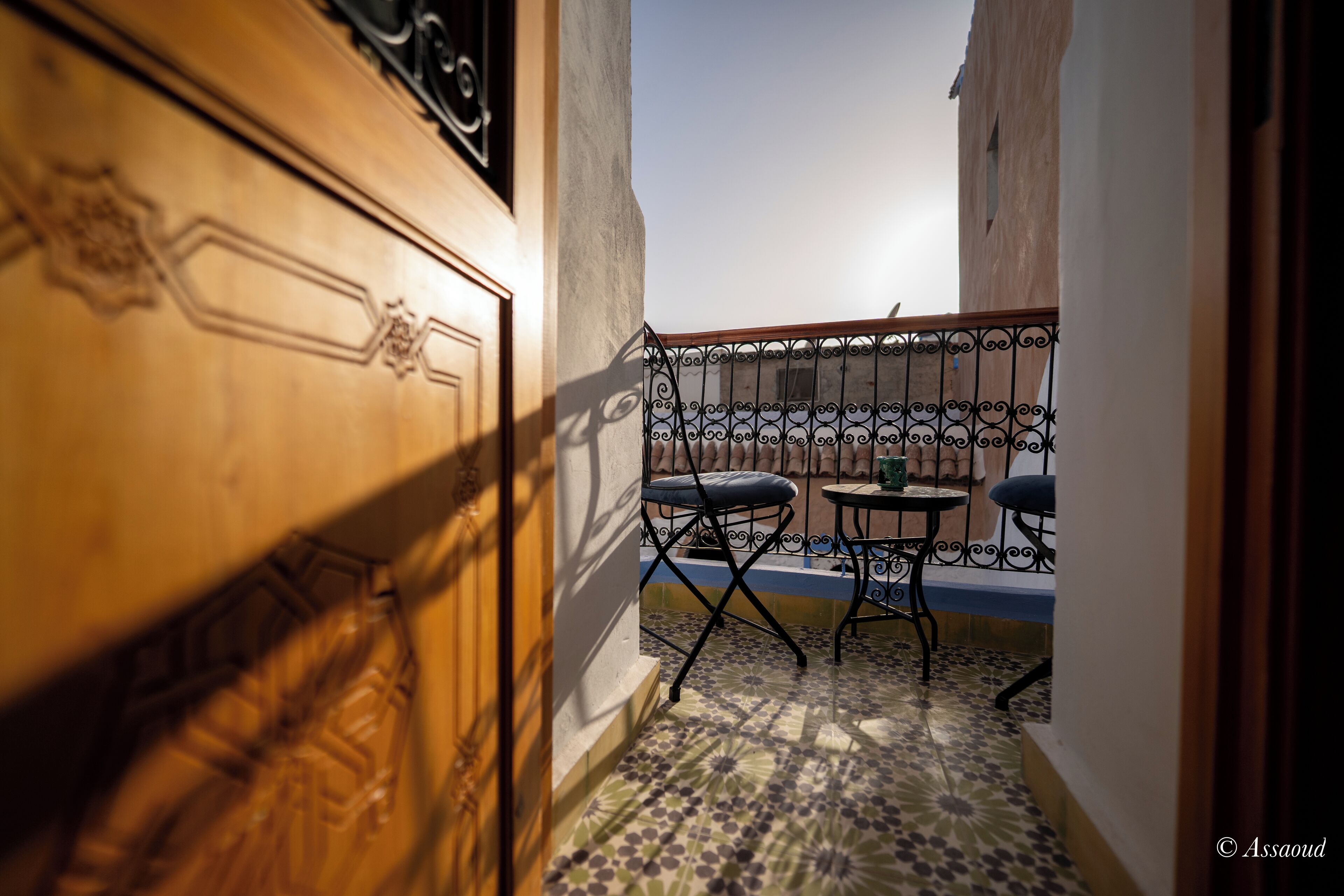 A narrow balcony with a tiled floor, two chairs, and a small table.
